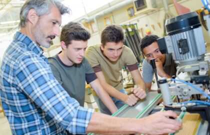 Man teaching boys how to use machine